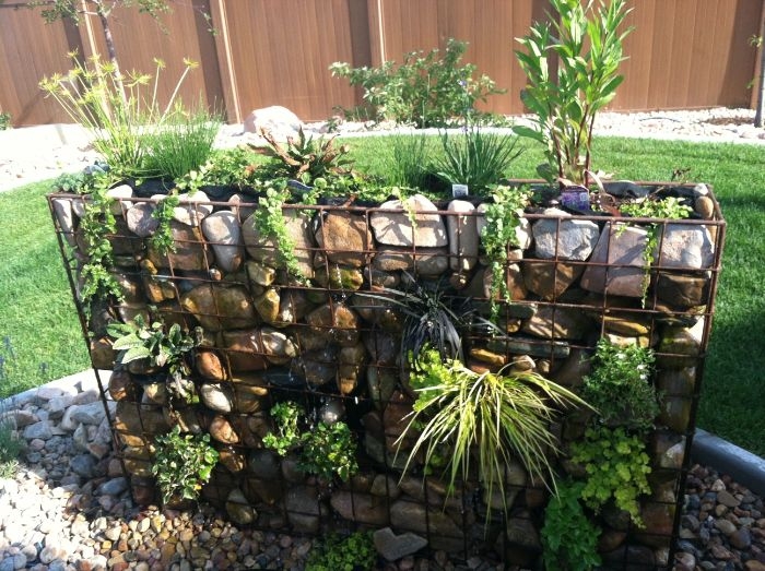 grand bac grille metallique aux pierres et plantes vertes pour separer et decorer un jardin
