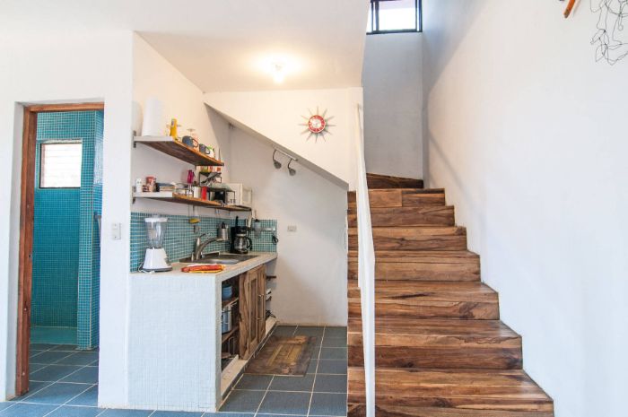 kitchenette blanche sous escalier avec portes de bois étagères bois ouvertes credence carrelage bleu