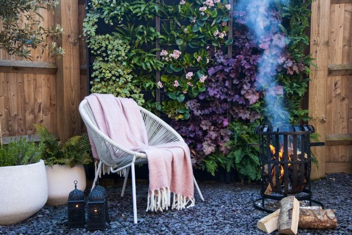 salon de jardin cocooning avec chaises en metale et couverture moelleuses gravier pots fleuris brise vue naturel