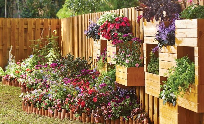 separation jardin exterieur mur de bois avec plusiuers bacs de fleurs parterre de fleus colorée jardin de reve