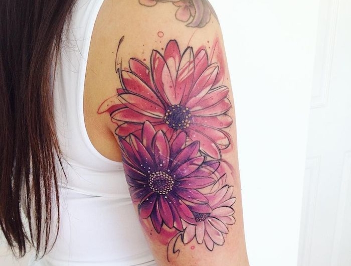 tatouage feminine sur l epaule avec un dessins des marguerites enormes en couleurs rose et violet