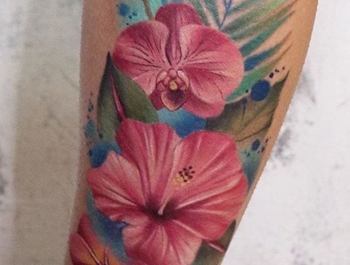 tatouage floral avec hibiscus et paprate en couleurs vif sur l avant bras