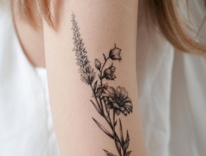 tatouage floral delicate sur le bras d une femme vetue en blanc