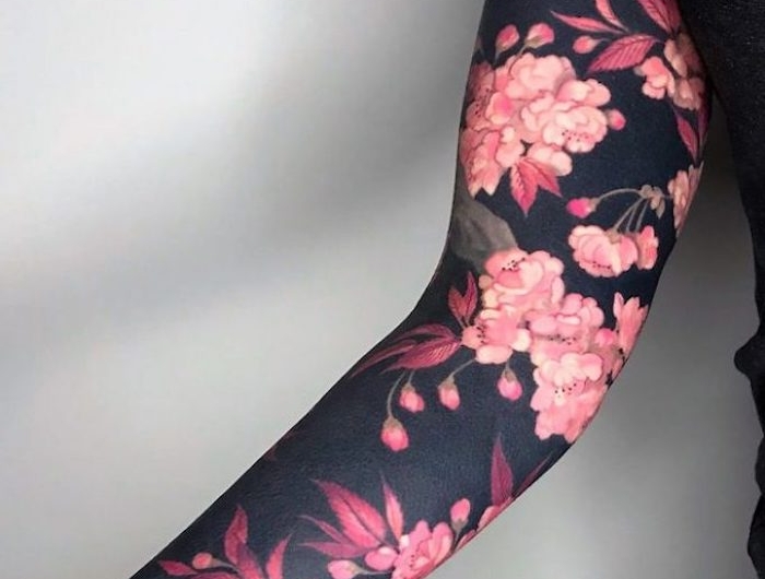 tatouage renaissance avec des fleurs roses au fond noir sur le bras