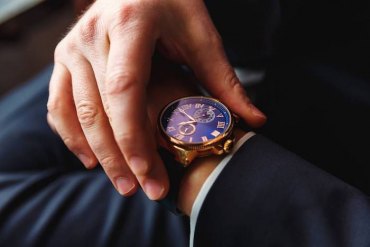 un homme en costume qui ajuste le montre autour sa poignée