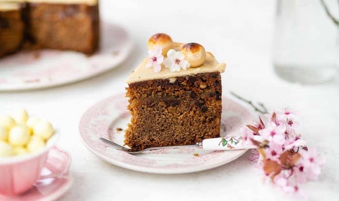 un morceau de gateau simnel dans petite assiettte décoré des fleurs printaniers