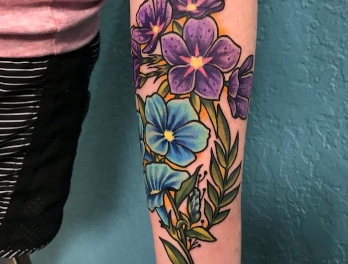 un tatouage bras femme fleur au fond bleu avec des fleurs en style new school