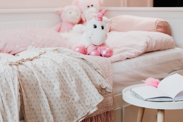 une chambre de petite fille avec une robe et un licorne en peouche sur le lit