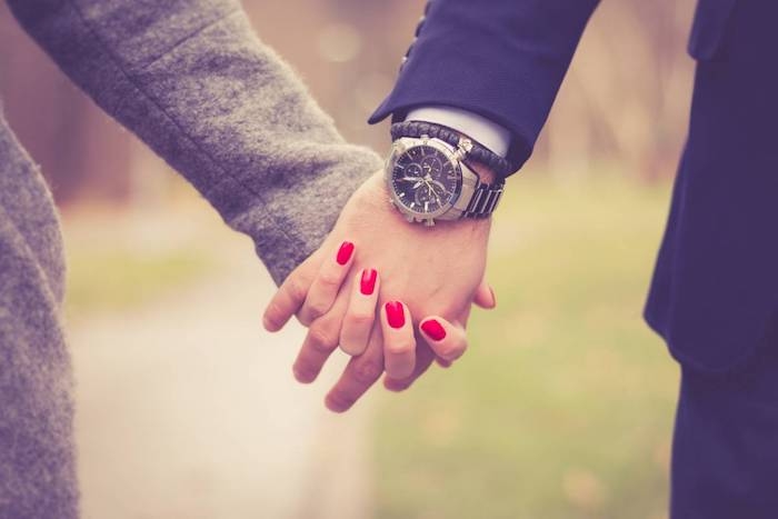 une couple qui se tient le mains montre masculin et des ongles en rouge