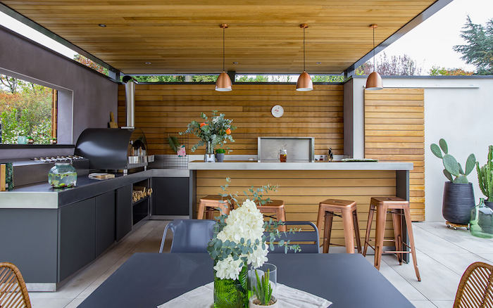 une cusine veranda moderne avec des surfaces en bois et des meubleus cuivrés des grands cactus au fond