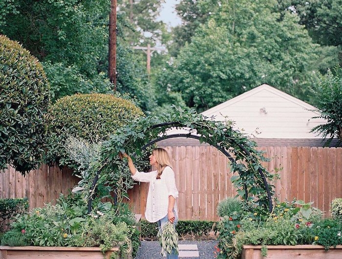 une femme dans le jardin sous un arc en verdure cuillit des feuilles idee bordure jardin recup