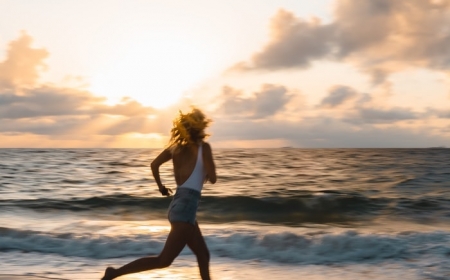 une femme en short jean cours a la plage a la leve de soleil