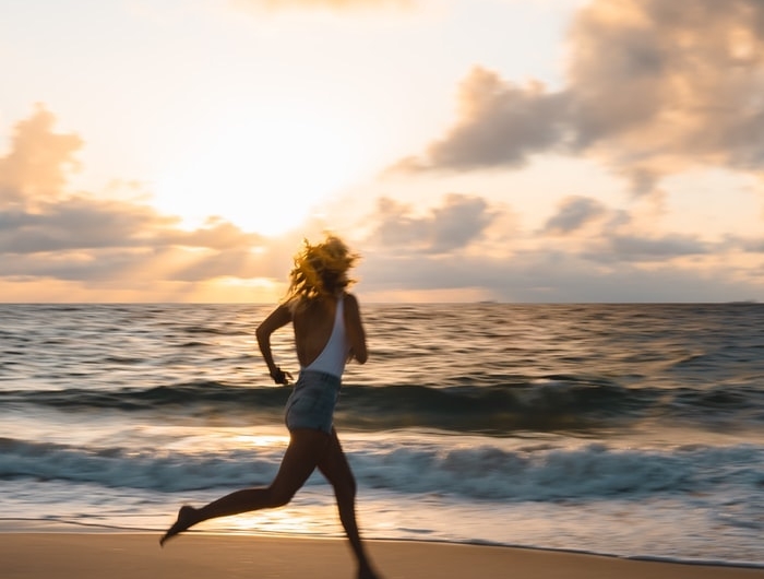 une femme en short jean cours a la plage a la leve de soleil
