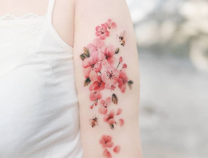 une femme en top banc avec un fmeur de cerisier tatouage fin au bras