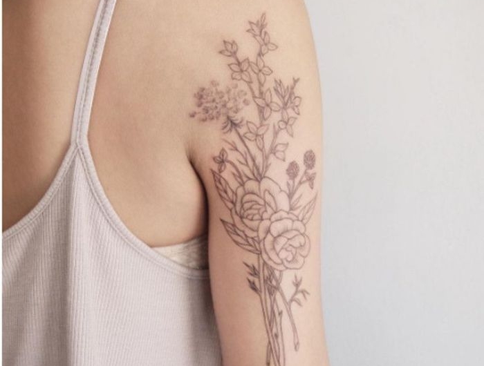une femme en top beige et tatouage plante sur le bras