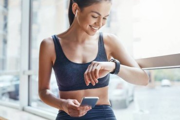 une femme en vetements de sport regarde le montre sur sa poignée portable dans le main