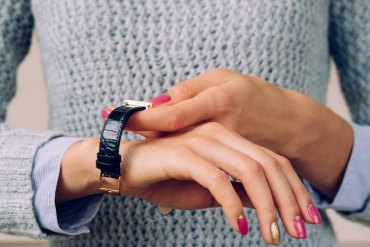 une femme qui se met un montre avec elements dorés sur la poignée