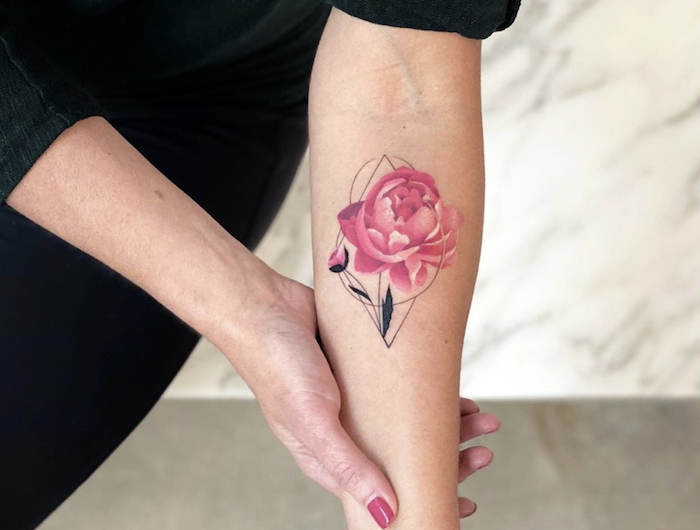 une femme qui se tient le bras avec une tatouage pivoine aux ornements geometriques.jpg