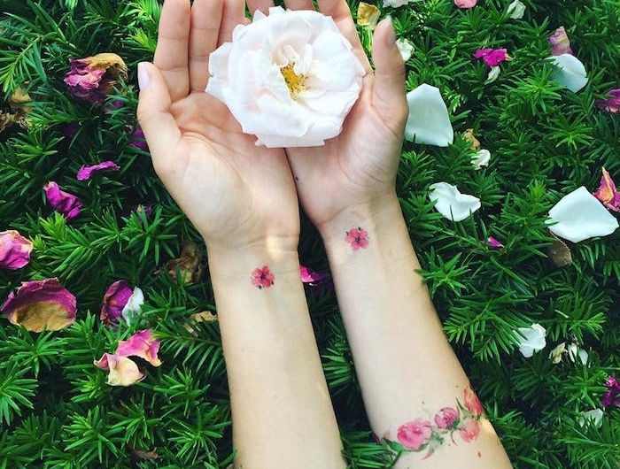 une femme qui tient rose blanche avec un tatouage nature sur les pognets