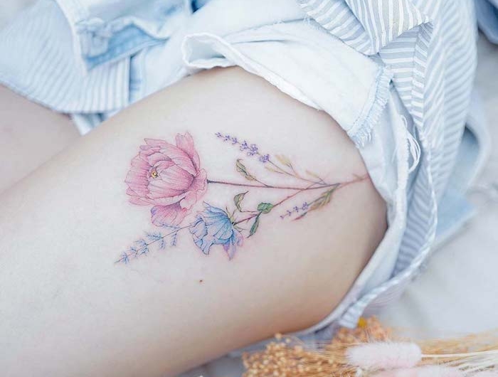 une femme vetue en pyjama avec un tatouage des fleurs de champ sur la cuisse