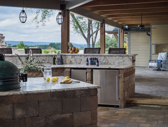 une grande veranda extérieures équipée de cuisine et d une grille avec vue vers le champ