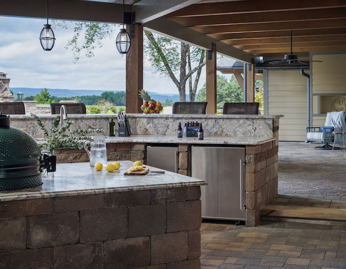 une grande veranda extérieures équipée de cuisine et d une grille avec vue vers le champ