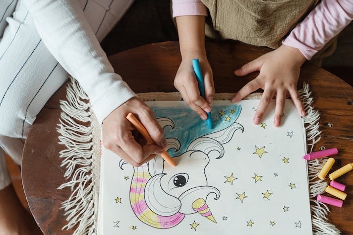 une petite fille et sa maman dessinent un licorne sur papier blanc
