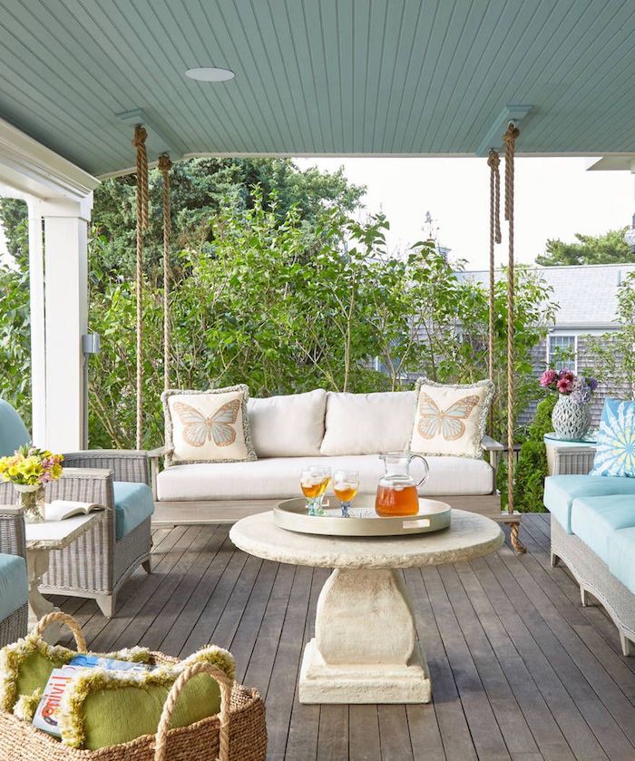 une veranda avec des canapés en rotin et un table en pierre naturelle ronde au milieu
