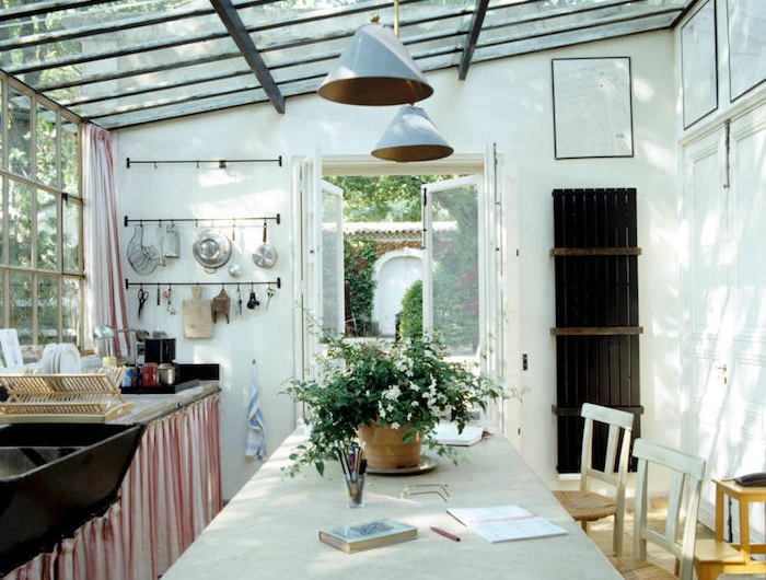 une veranda sous pergola aménagé d un style rustique et pas prétentieux avec des lampes pendantes et un pot a fleur au table