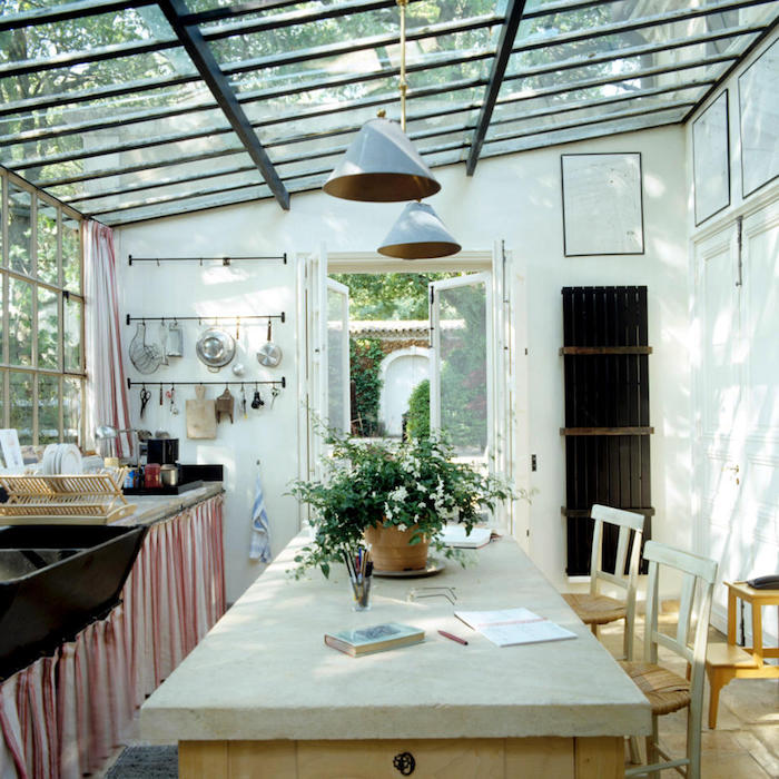 une veranda sous pergola aménagé d un style rustique et pas prétentieux avec des lampes pendantes et un pot a fleur au table