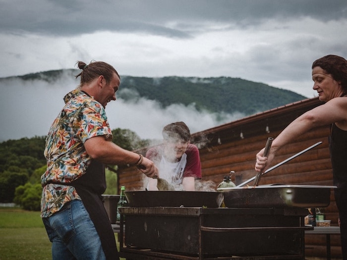 barbeque en dehors pelouse verte vue vers la montagne homme femme et garcon