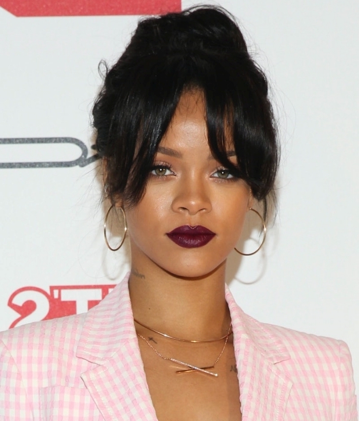 coiffure célébrité rihanna cheveux noirs chignon haut coupe avec frange sur le côté mèches tombantes visage