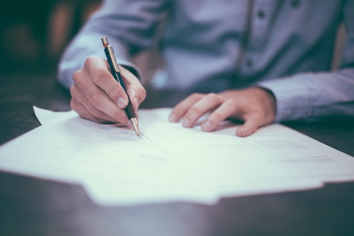 homme en chemise bleu document pour signer poses sur le bureau