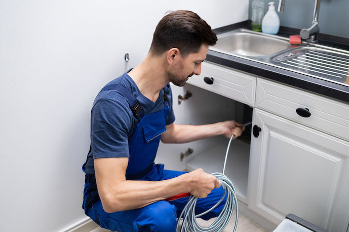 plumber cleaning clogged sink pipe