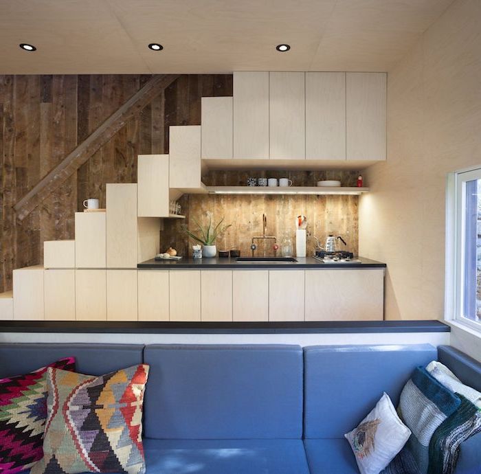 studio kitchenette boisée avec crédence bois plan de travail noir canapé bleu décoré de coussins bohème chic