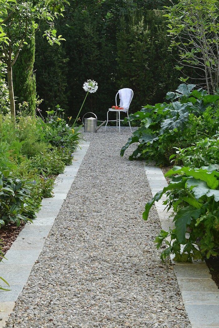 allée de jardin moderne en gravier bordure en pierre parterres en buissons et plantes vertes