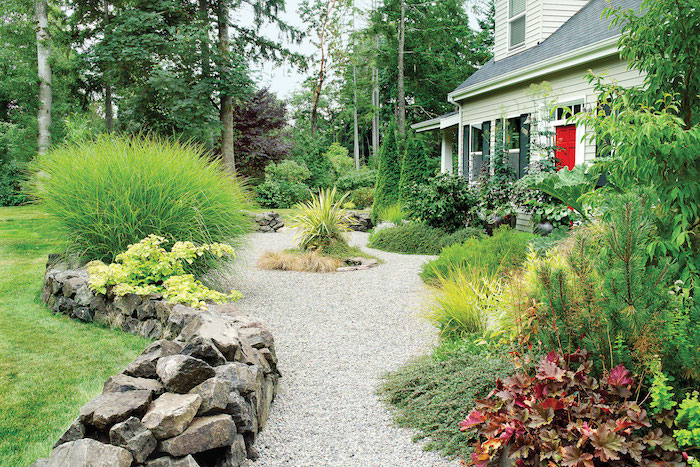 bordure de jardiin en pierre allée en gravier jardin avec buissons et des fleurs devant une belle maison