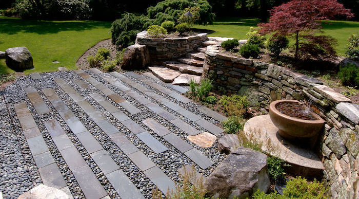 bordure de jardin en pierre allée an gravier et pierres arbres et buissons