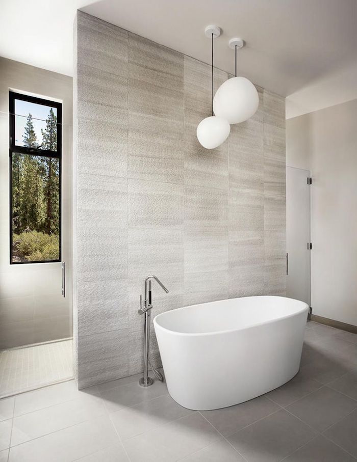carrelage travertin salle de bain en blanc et gris clair avec baignoire en faïance blanche