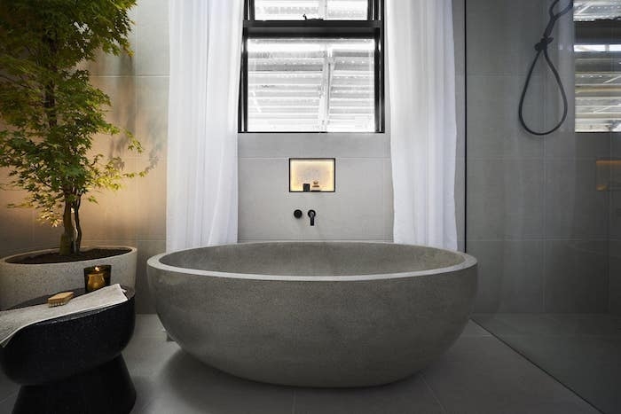 carrelage travertin salle de bain gris baignoire en pierre naturelle rideaux blancs et plante