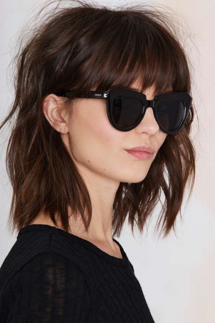 coupe carré avec frange brune aux lunettes de soleil noires rondes femme au top noir