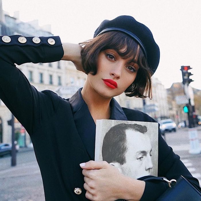 coupe carré avec frange droite légèrement ondulée femme à la tenue noire chapeau noir et lèvres rouges