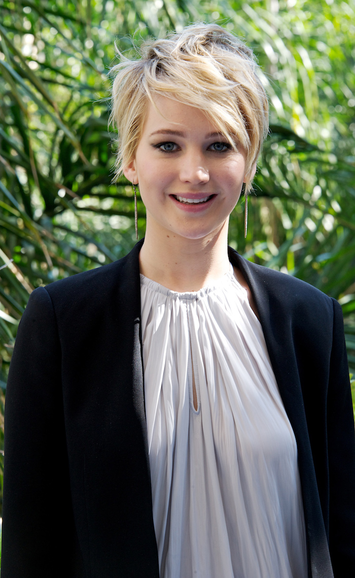 coupe courte asymétrique blonde avec frange effilée sur le cote jennifer lawrence en top gris et veste noire