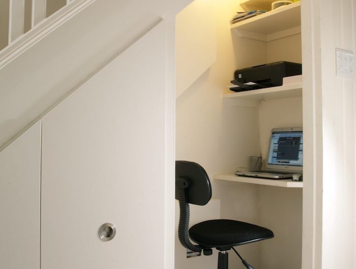 escalier avec rangement cloison peinte en blanc chaise de bureau noir bureau simple et étagères blancs