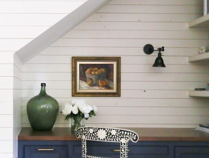 espace perdu cage d escalier étagères blanches mur de planches de bois blanc contraste avec le bureau bleu vase vert cadre de photo sur le mur chaise en noir et blanc