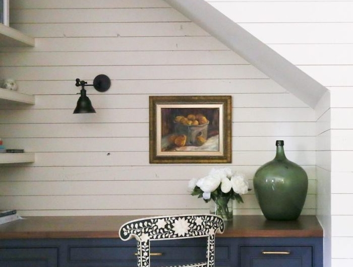espace perdu cage d escalier étagères blanches mur de planches de bois blanc contraste avec le bureau bleu vase vert cadre de photo sur le mur chaise en noir et blanc