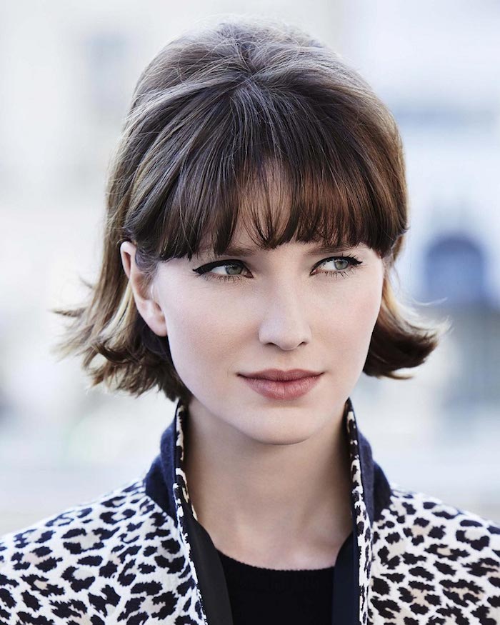 moderne coupe cheveux court avec frange droite effilée femme au maquillage discret à la veste en blanc et noir