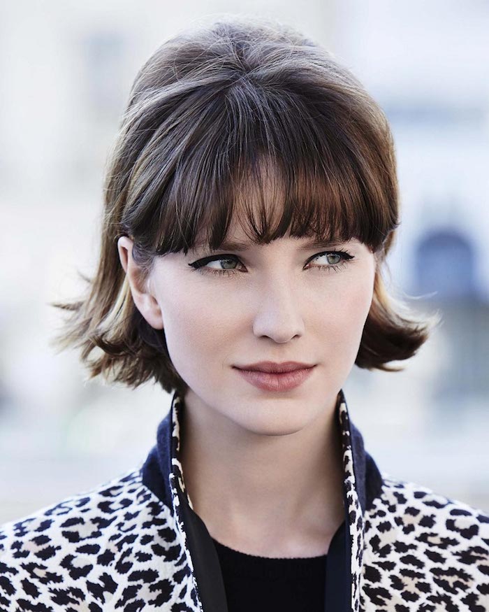 Modern short haircut with straight pointed bangs for women with hidden makeup in a white and black jacket