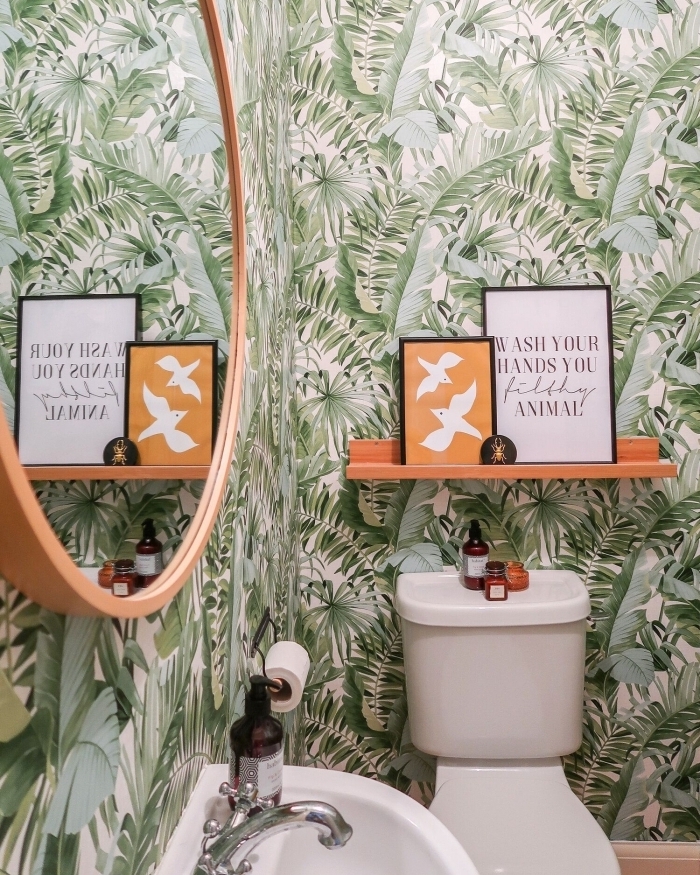 papier peint toilette motifs jungles feuilles vertes étagère bois peinture orange cadres décoratifs