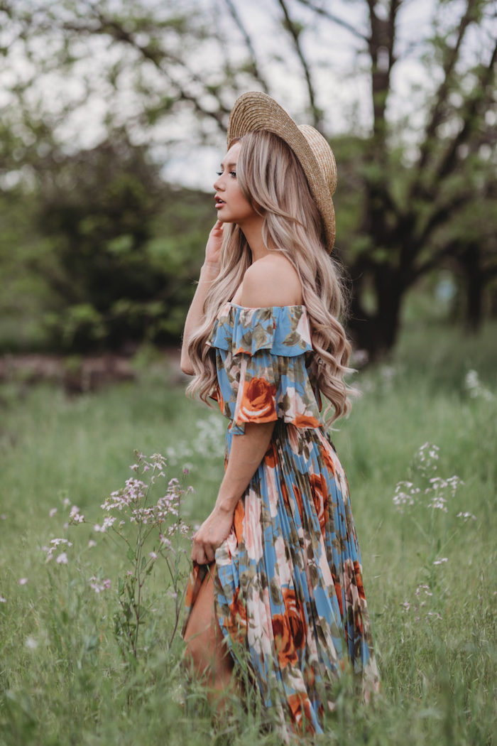 robe longue fleurie bohème femme au cheveux blonds à la capeline dans des champs